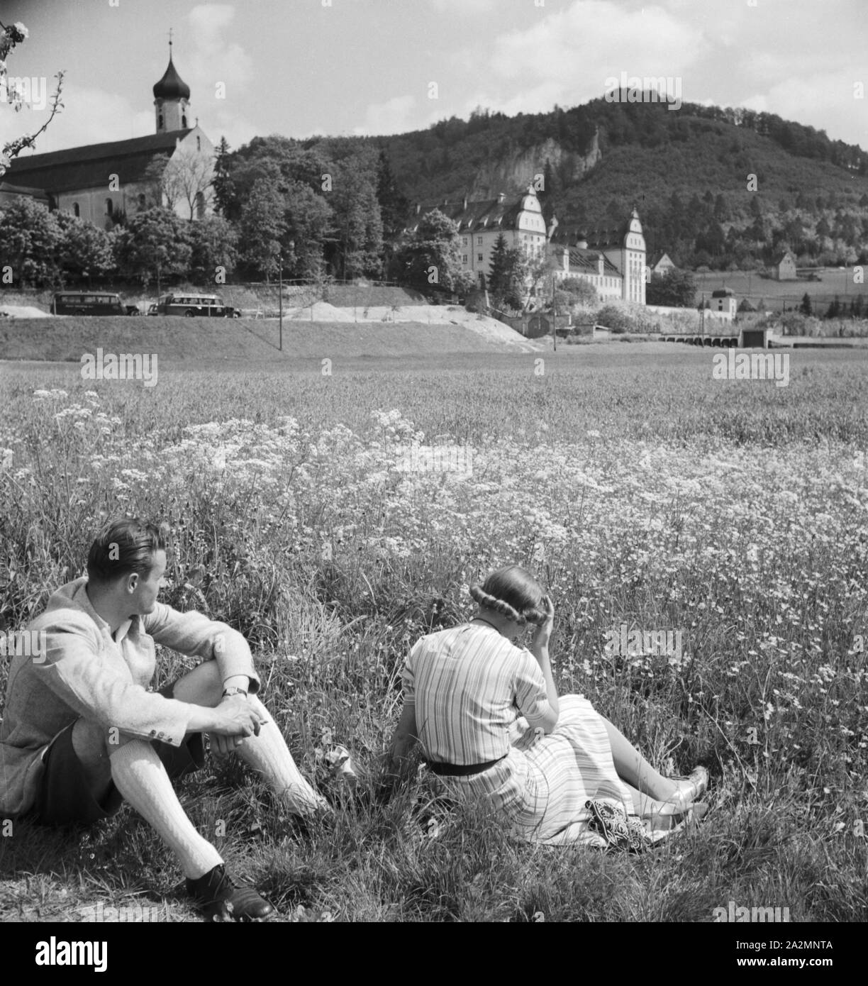 Ein junges Paar sitzt in einer Wiese, Deutschland 1930er Jahre. A young couple siiting in a lawn, Germany 1930s. Stock Photo