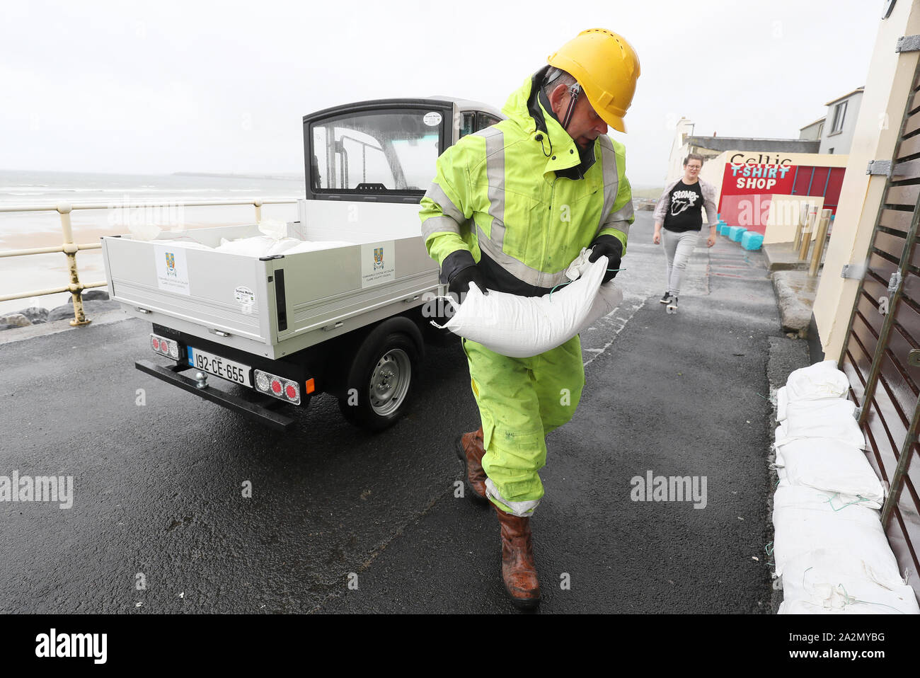 Members of Clare County council place sandbags at shops on the sea front in Lahinch, County Clare, on the West Coast of Ireland in preparation for storm Lorenzo, as a status orange wind warning and a yellow rain warning have been issued. Stock Photo