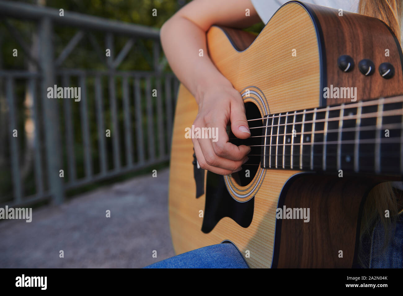 Girl's hand plays the acoustic guitar. Young musician making money on the bridge. Street music concept. Closeup. Stock Photo
