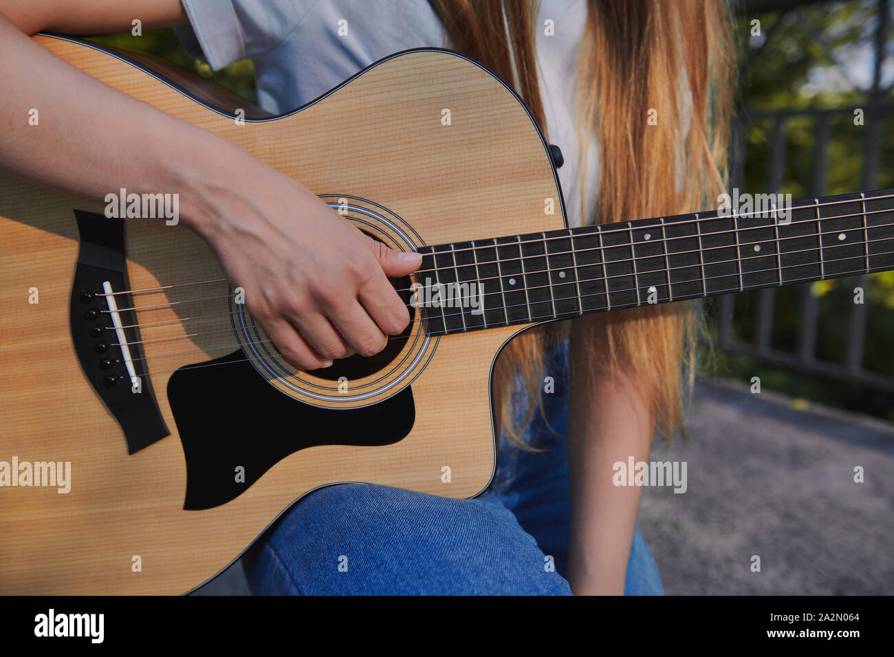Girl's hand plays the acoustic guitar. Young musician making money on the bridge. Street music concept. Closeup. Stock Photo