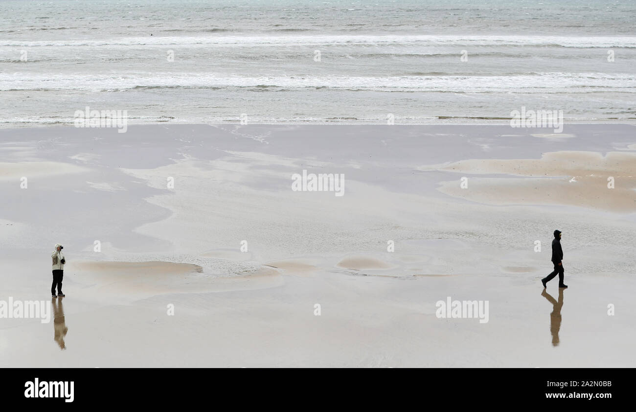 People walk on the beach in Lahinch, County Clare, on the West Coast of Ireland as storm Lorenzo is expected to make landfall, with a status orange wind warning and a yellow rain warning having been issued. Stock Photo