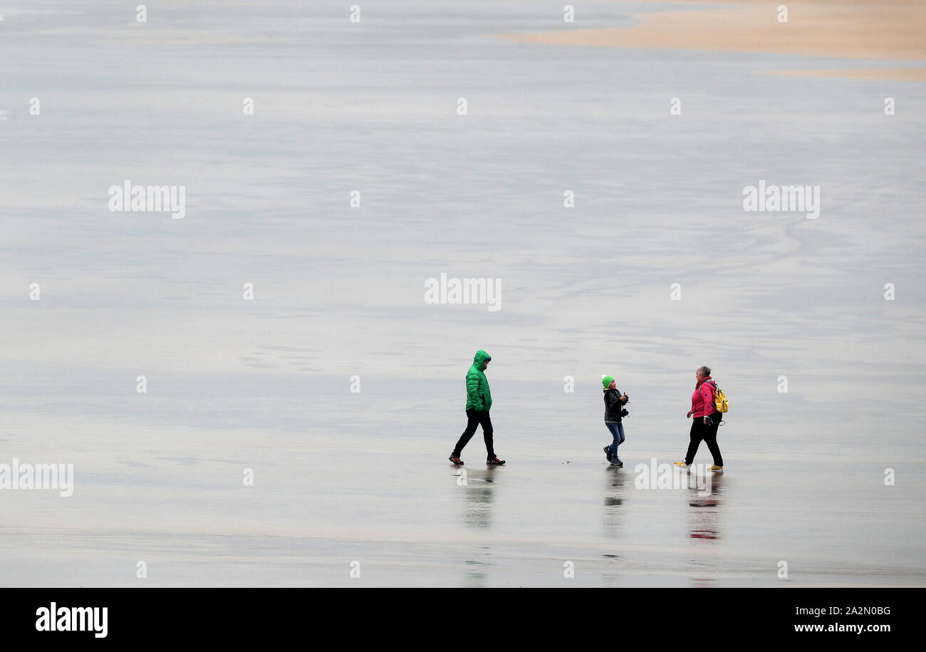 People walk on the beach in Lahinch, County Clare, on the West Coast of Ireland as storm Lorenzo is expected to make landfall, with a status orange wind warning and a yellow rain warning having been issued. Stock Photo