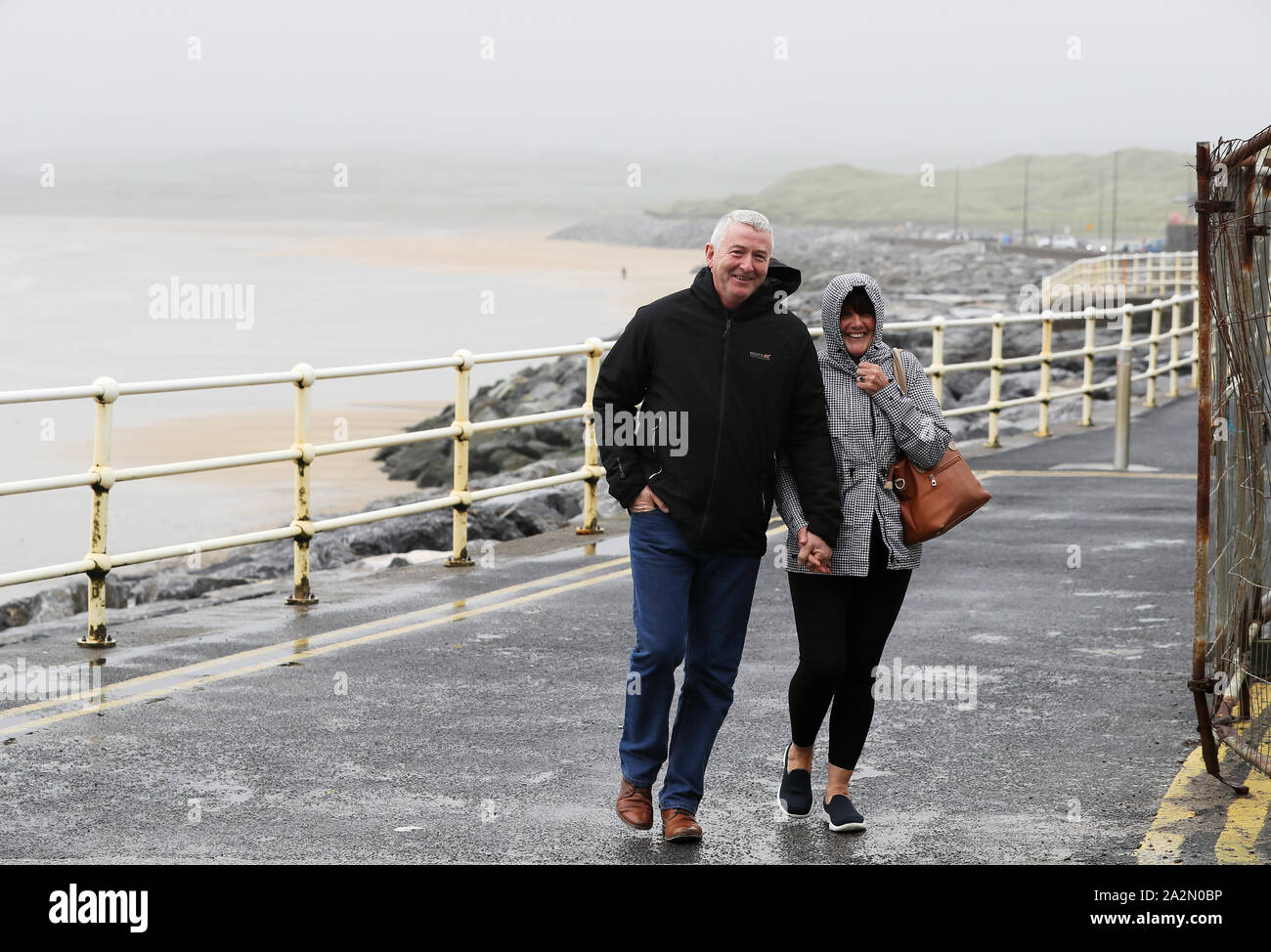 People walk along the sea front in Lahinch, County Clare, on the West Coast of Ireland as storm Lorenzo is expected to make landfall, with a status orange wind warning and a yellow rain warning having been issued. Stock Photo