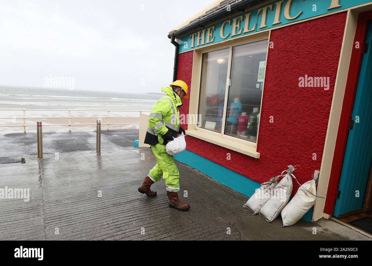 Members of Clare County council place sandbags at shops on the sea front in Lahinch, County Clare, on the West Coast of Ireland in preparation for storm Lorenzo, as a status orange wind warning and a yellow rain warning have been issued. Stock Photo