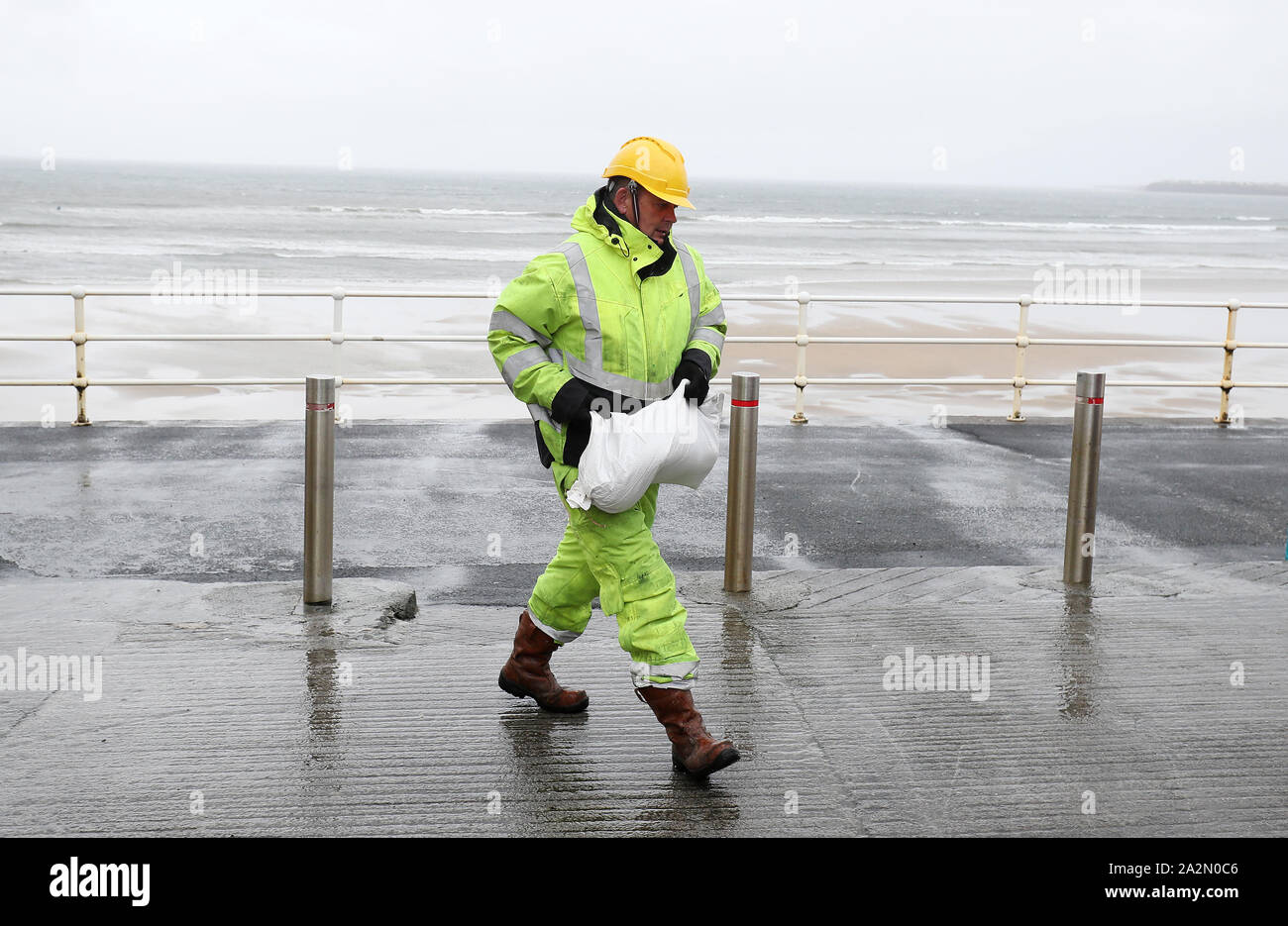 Members of Clare County council place sandbags at shops on the sea front in Lahinch, County Clare, on the West Coast of Ireland in preparation for storm Lorenzo, as a status orange wind warning and a yellow rain warning have been issued. Stock Photo