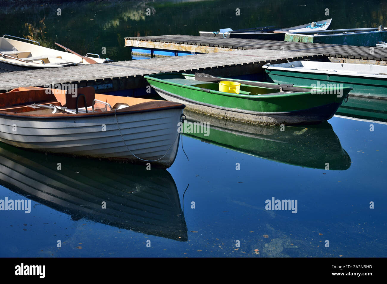 Some angler boats of different colors in a lake, reflecting in the water. Stock Photo