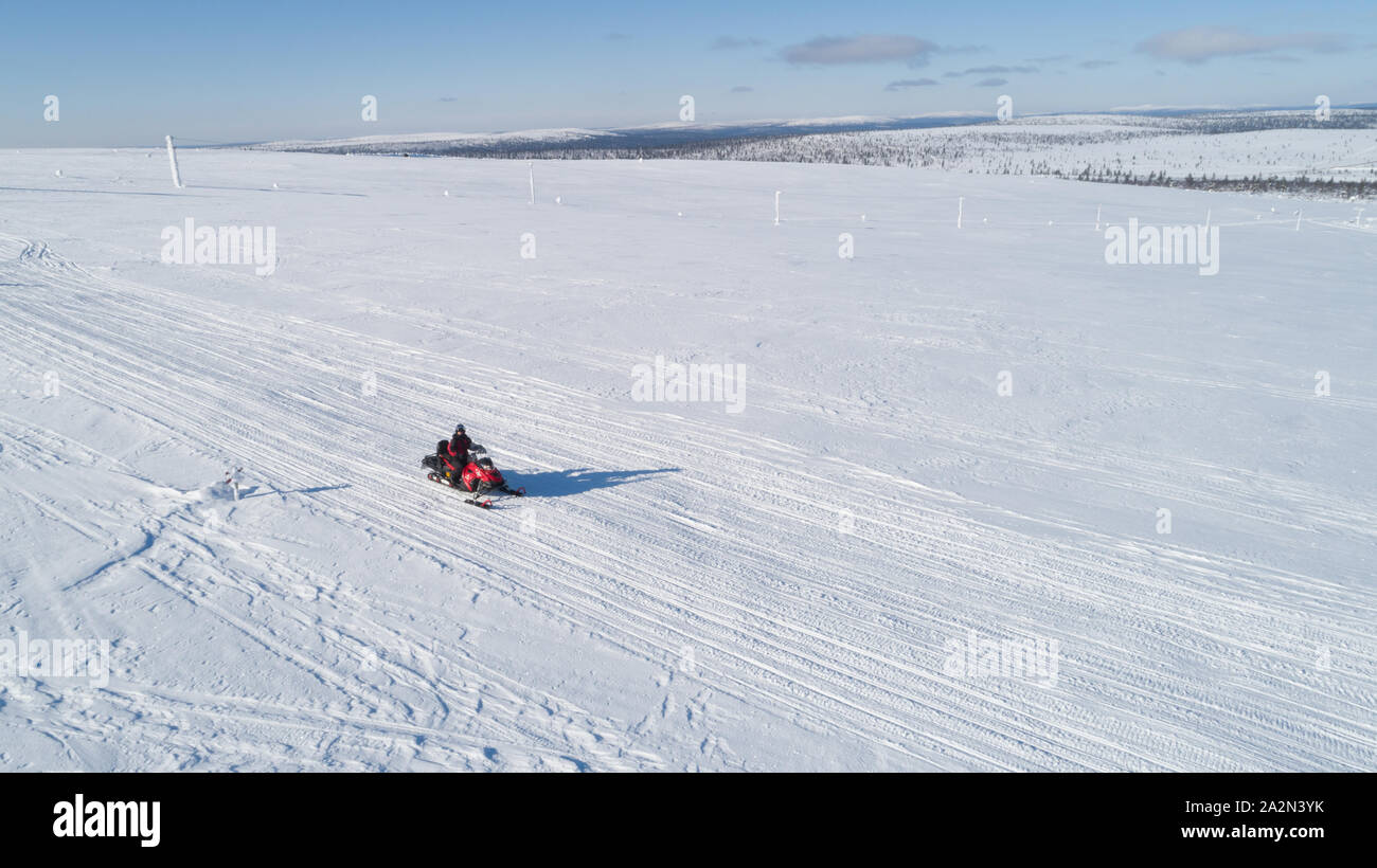 Aerial drone image of a woman driving snowmobile at winter wonderland Lapland. Stock Photo