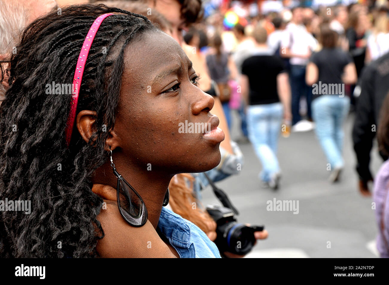 A beautiful black woman watches the participants of the gay pride parade passing by in Paris, France, Europe. Stock Photo