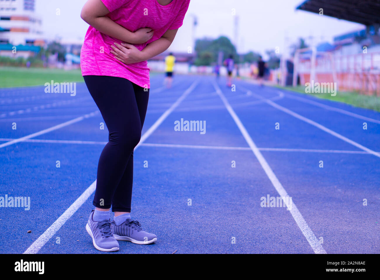 Sport girl holding abdomen with her hands in stomach pain after jogging