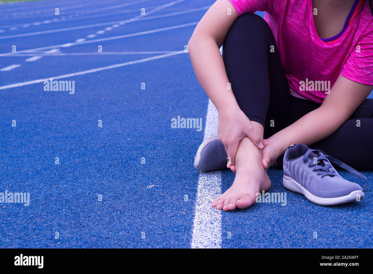Ankle sprained. Young woman suffering from an ankle injury while ...