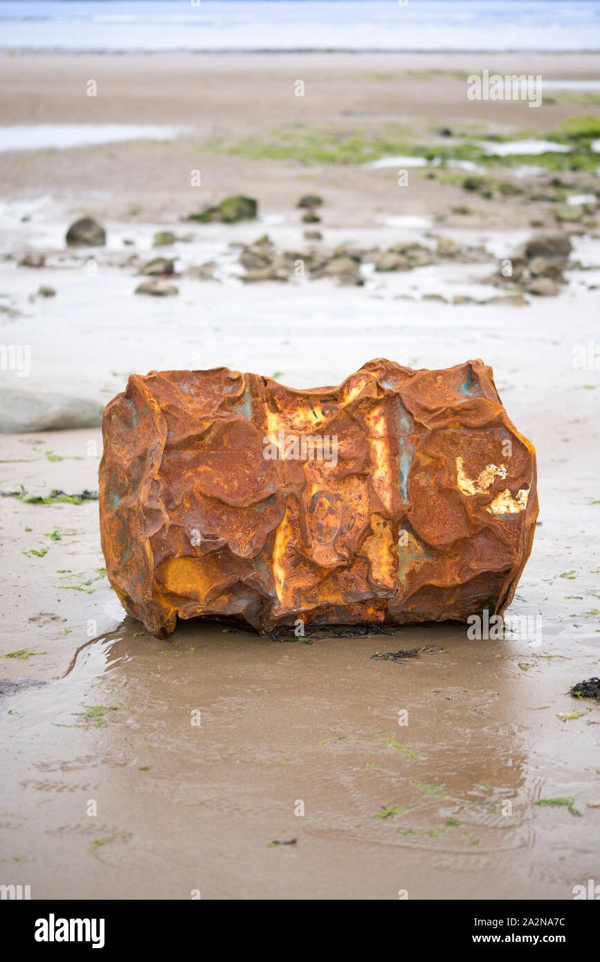 rusty metal barrel washed up on the beach Stock Photo