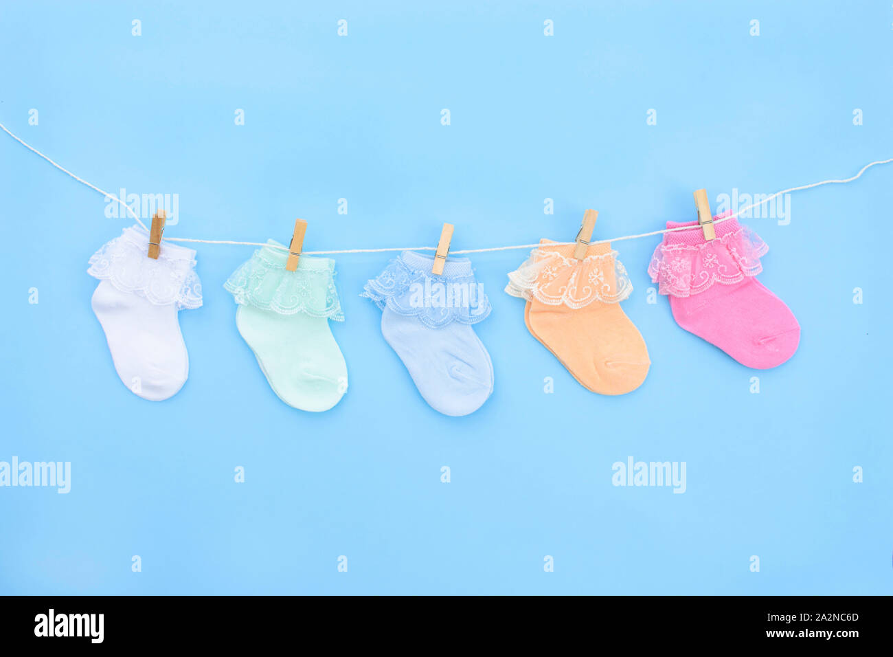 Colorful cute baby socks hanging on the clothesline on blue background