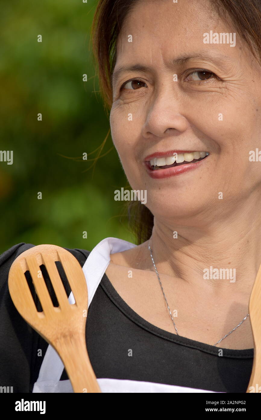Smiling Old Asian Female Cook Wearing Apron With Utensils Stock Photo