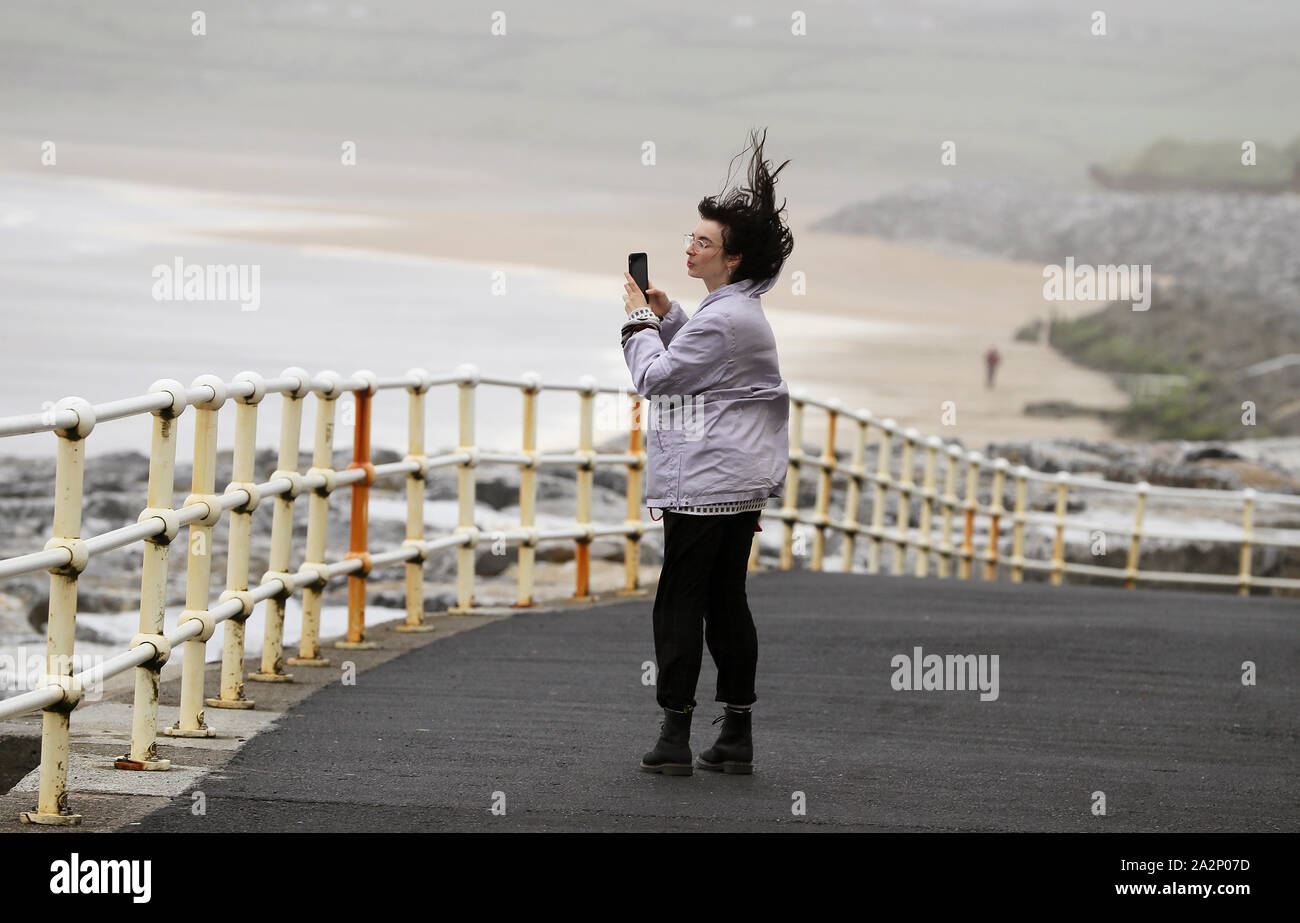 People walk along the sea front in Lahinch, County Clare, on the West Coast of Ireland as storm Lorenzo makes landfall, with a status orange wind warning and a yellow rain warning having been issued. Stock Photo