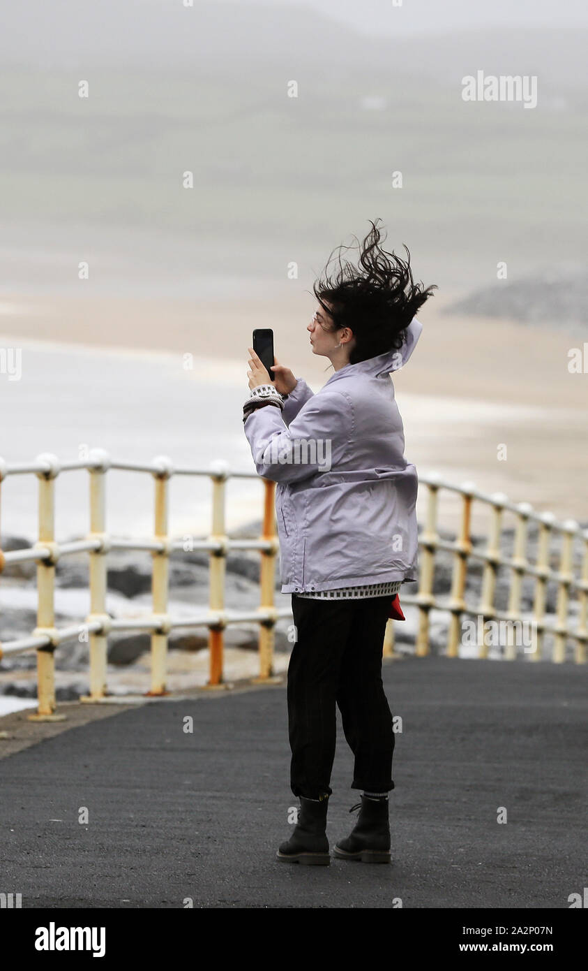 People walk along the sea front in Lahinch, County Clare, on the West Coast of Ireland as storm Lorenzo makes landfall, with a status orange wind warning and a yellow rain warning having been issued. Stock Photo