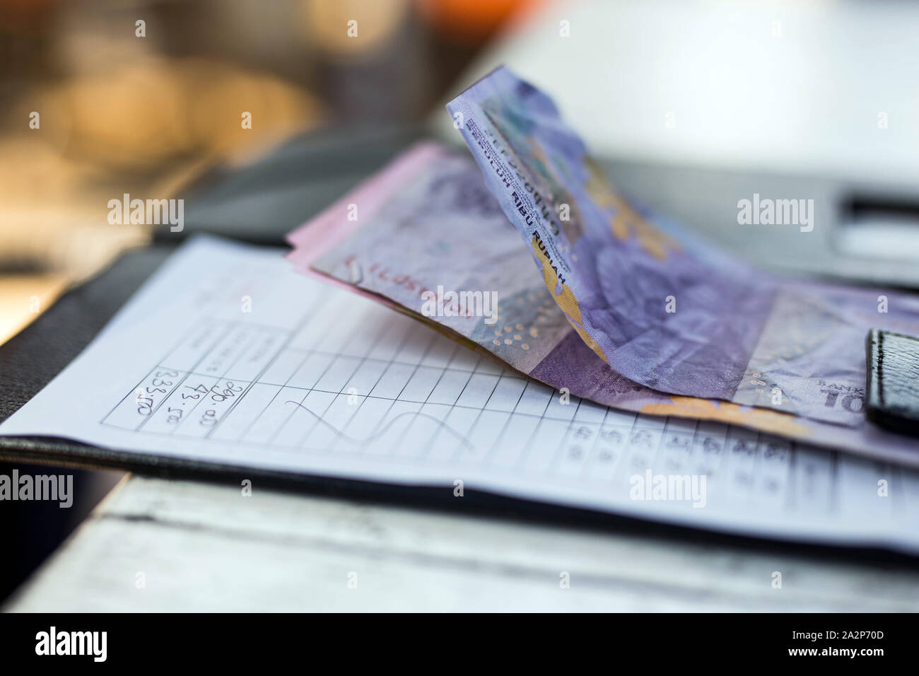 Restaurant bill with money on payment tray on the table, money is