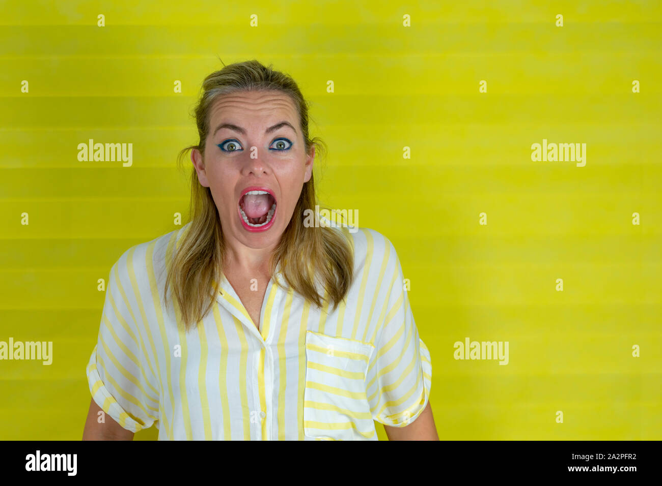 young woman on a yellow background with surprise expression and excited face - image Stock Photo
