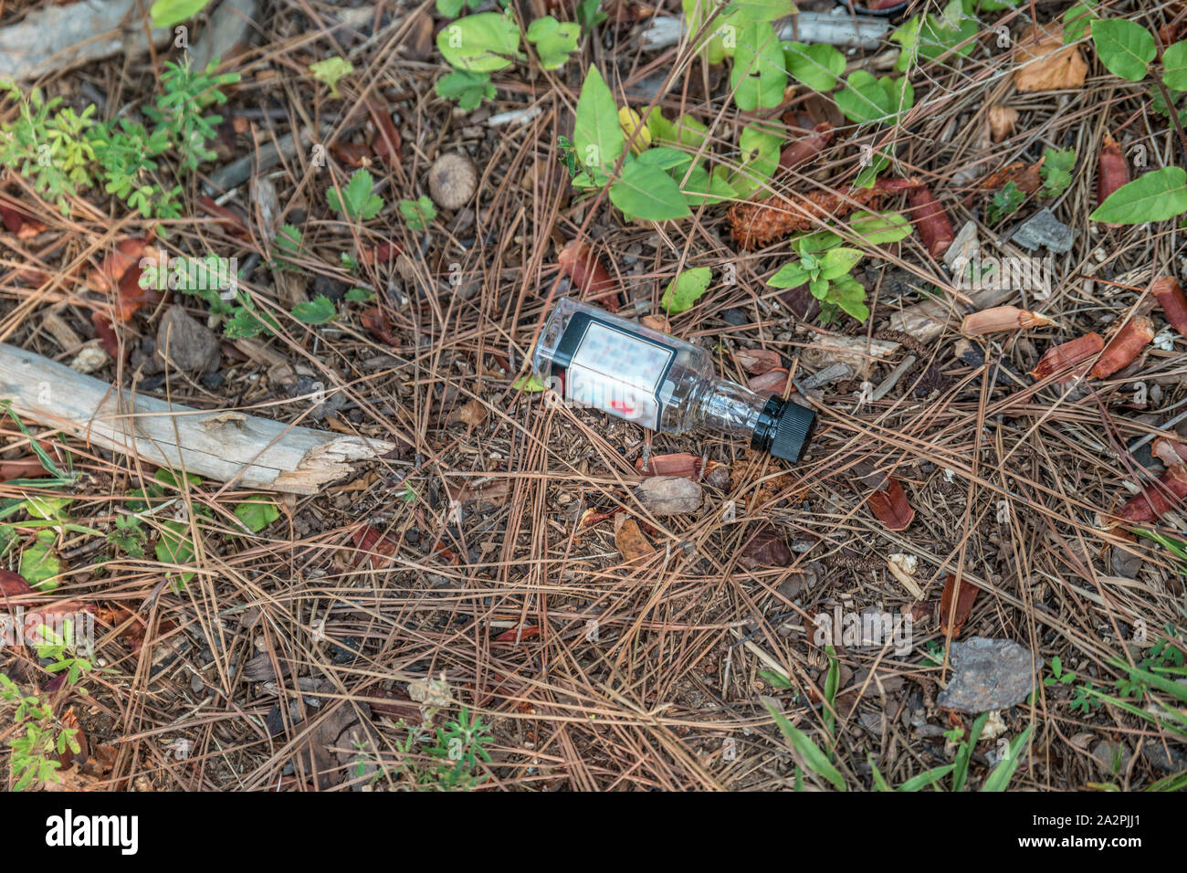 A miniature glass bottle of alcohol dumped on the ground as garbage in ...