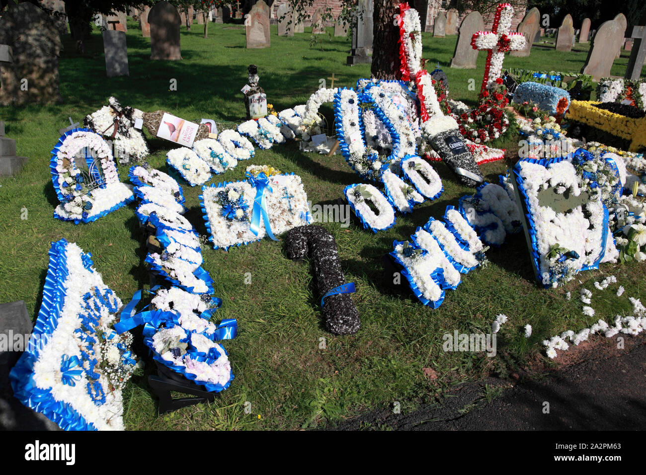 A much decorated grave including floral signs for Husband, Dad, Brother and Grandad (on the left) Stock Photo