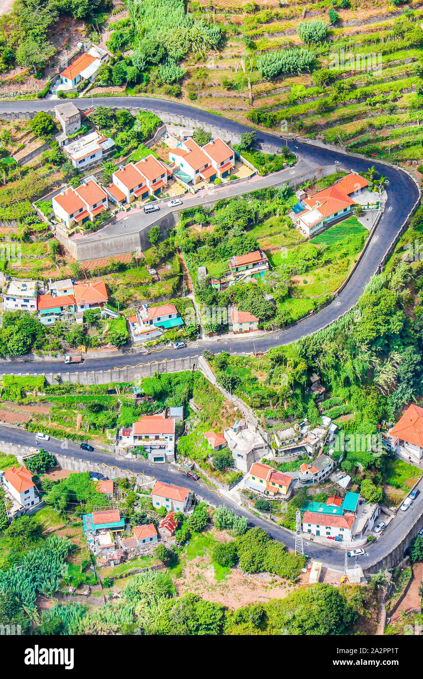 Aerial view of a village Curral das Freiras, Madeira Island, Portugal. Countryside houses, green terraced fields, and scenic serpentine road photographed from above. Aerial landscape. Travel spot. Stock Photo