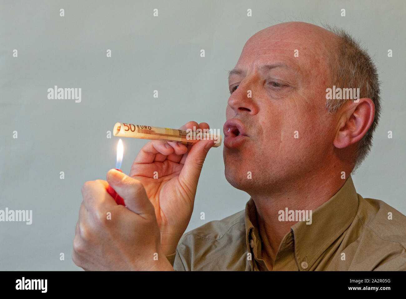 A man is smoking a 50 Euro note. Stock Photo