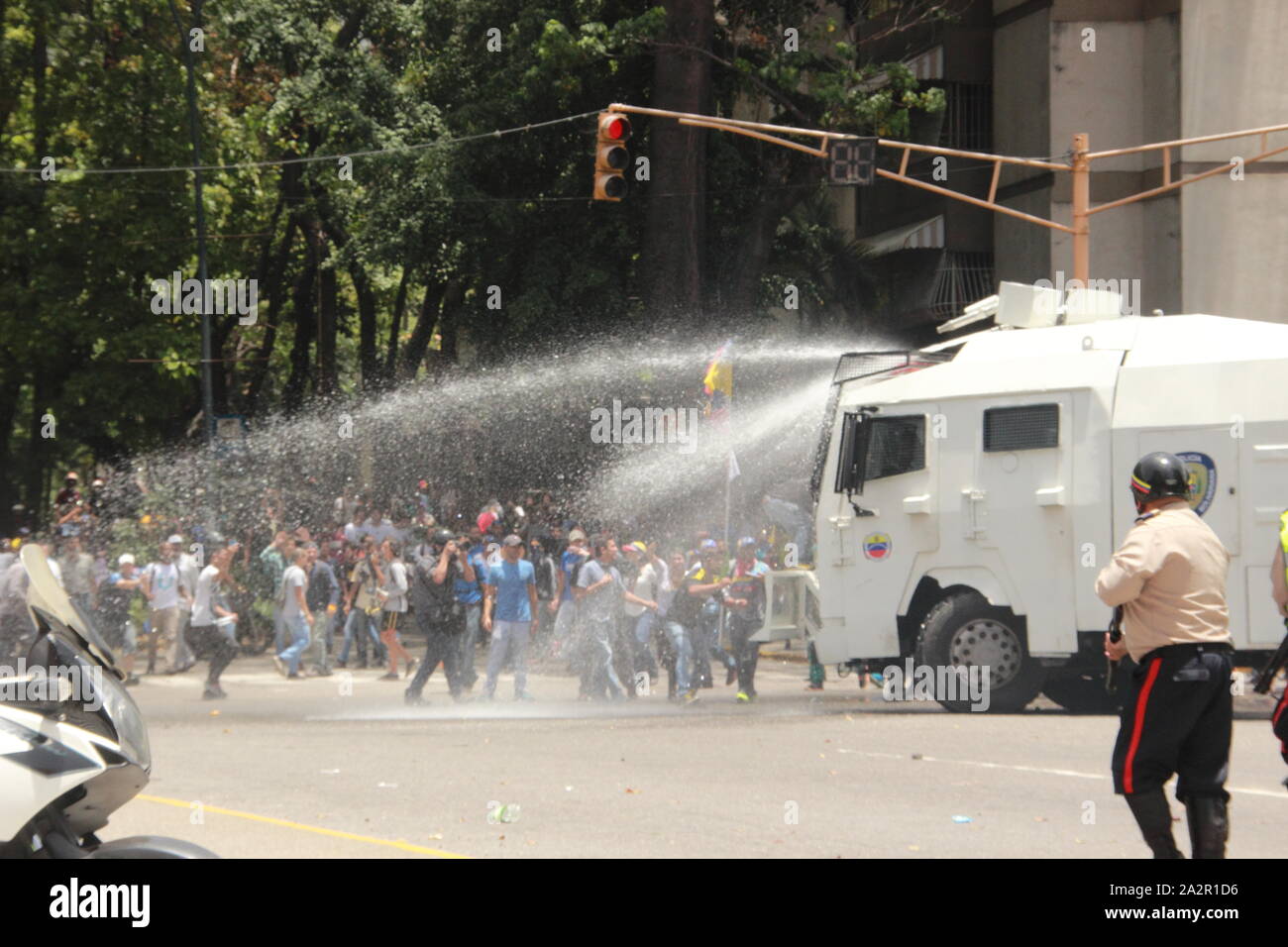 A police water cannon disperses demonstrators during an opposition rally against Nicolas Maduro regime in Caracas Stock Photo