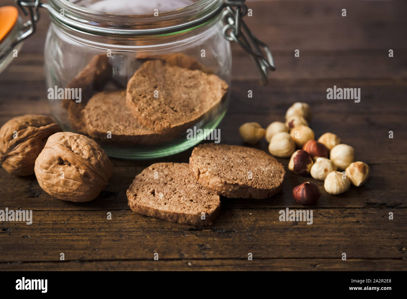 Homemade wholegrain cookies with nuts on a rustic wooden table. Healthy vegan wholegrain cookies. Some of them in a jar. Stock Photo