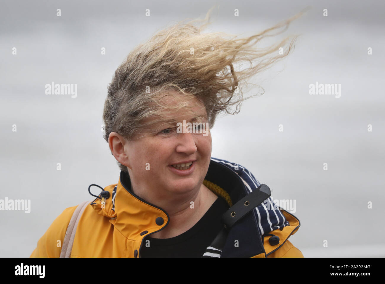 A woman walks along the sea front in Lahinch, County Clare, on the West Coast of Ireland as storm Lorenzo makes landfall, with a status orange wind warning and a yellow rain warning having been issued. Stock Photo