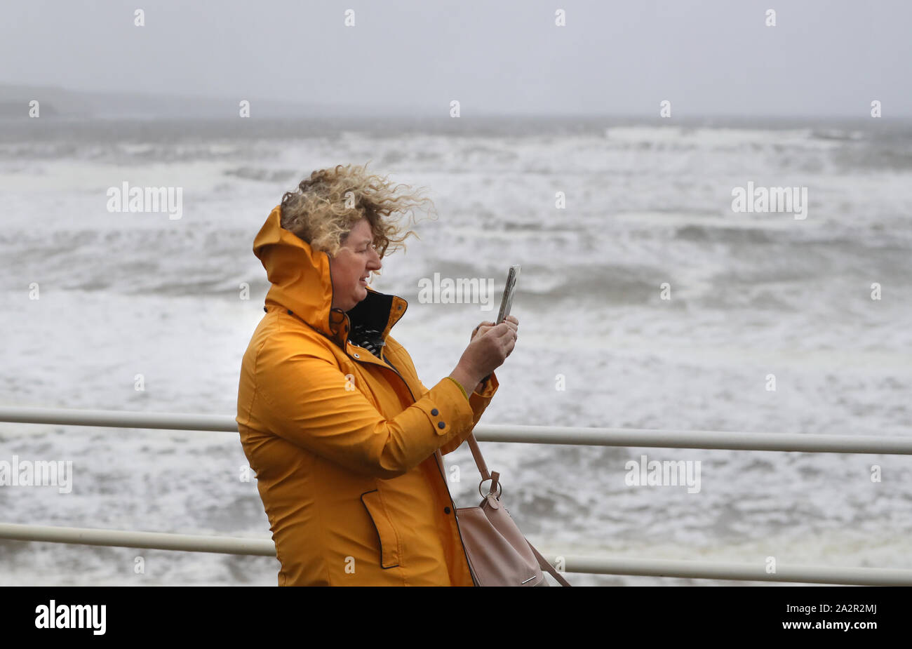 A woman walks along the sea front in Lahinch, County Clare, on the West Coast of Ireland as storm Lorenzo makes landfall, with a status orange wind warning and a yellow rain warning having been issued. Stock Photo