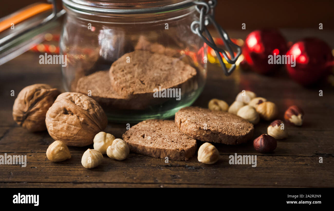 Homemade wholegrain cookies with nuts on a rustic wooden table with some christmas decoration. Some of the energetic cookies are in a jar as a christm Stock Photo
