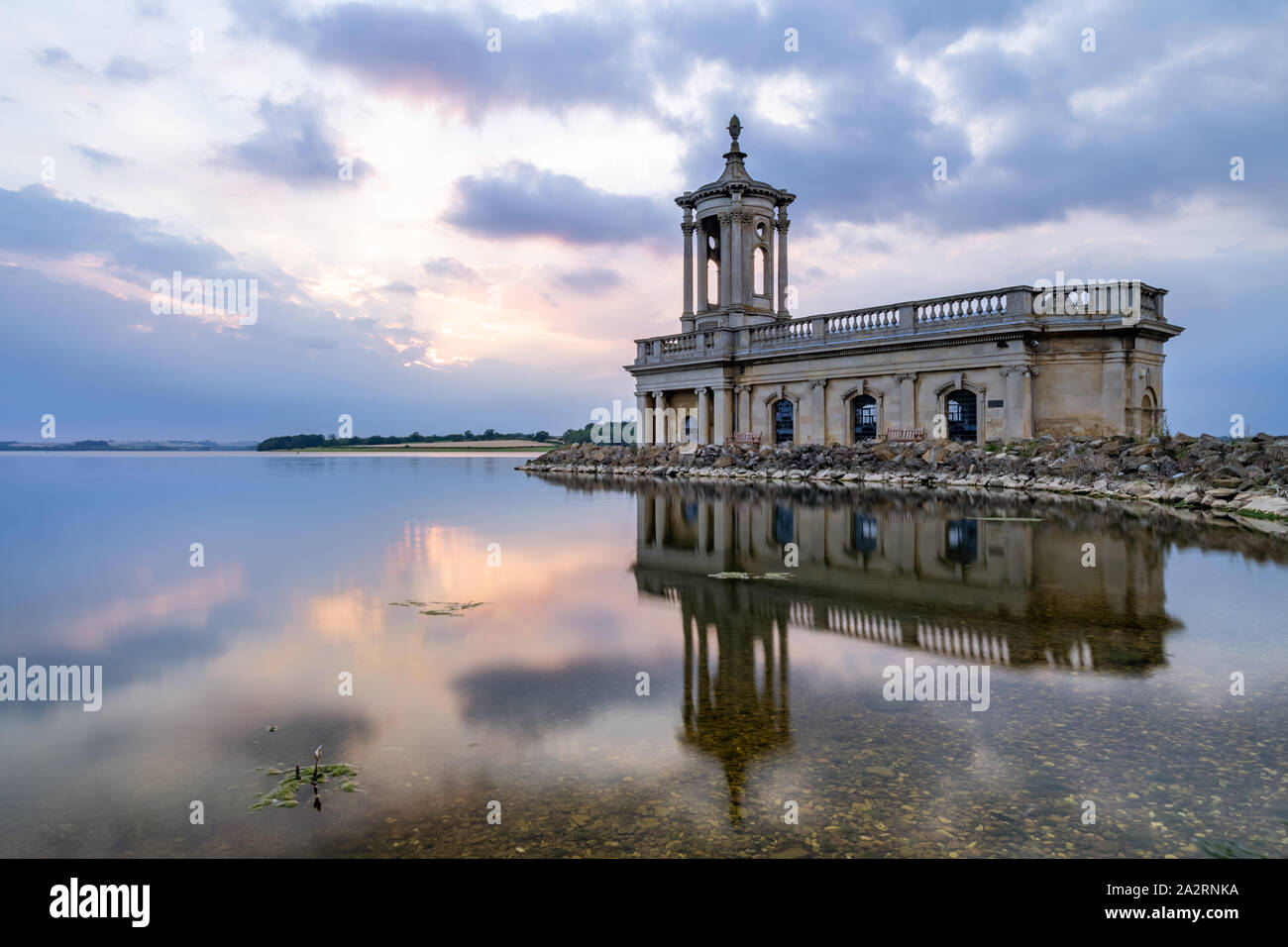 Normanton Church is reflected in a perfectly calm Rutland Water at sunset on a summer evening, the lower story concealed beneath the reservoir. Stock Photo