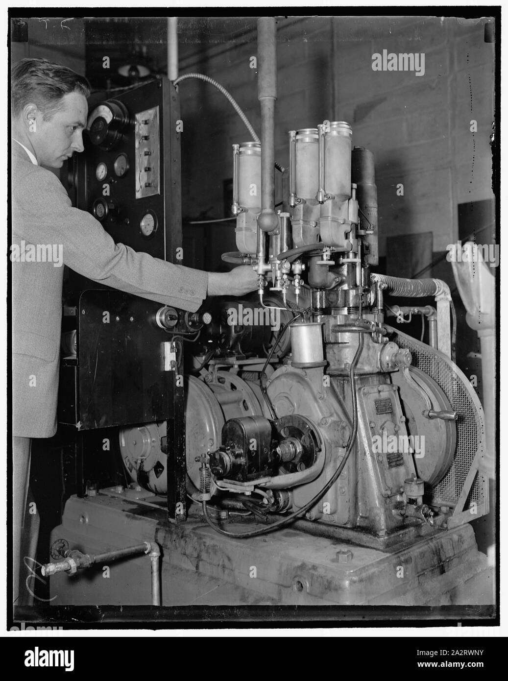 Rating gasolines at the Bureau of Standards. Washington, D.C., April 17. F.R. Carter of the U.S. Bureau of Standards is shown adjusting the mixture of gasoline to find out the rating in octane numbers of gasolines. The three carbureter shown in the foreground are each filled with a gasoline tow of which with a known octane rating and the third is filled with the sample to be tested, this machine has a variable compression ratio and can be changed while in motion Stock Photo