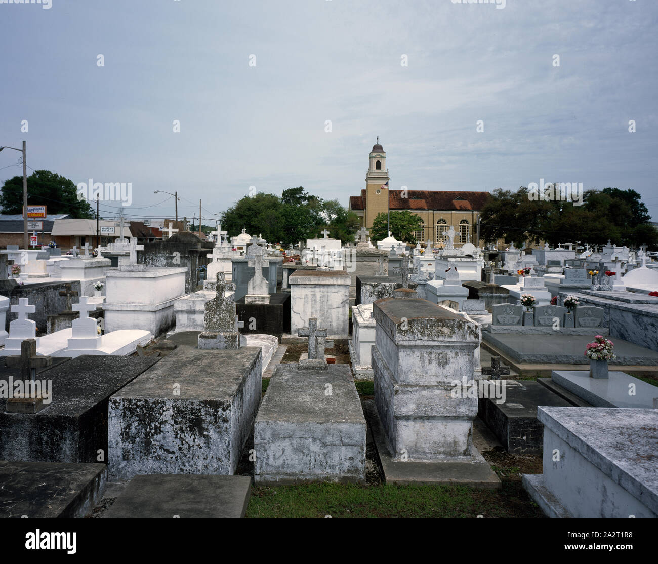 City of the Dead, in which tombs must be above ground because of the high water table in New Orleans, Louisiana  Location is actually Rayne Louisiana, not New Orleans. Visible beyond the cemetery of St. Joseph Catholic Church.  At left of the photo business visible include Champagne's Supermarket, The Spinner's Wheel, Rayne Rent-All, and Cox (cable tv/communications company). Stock Photo