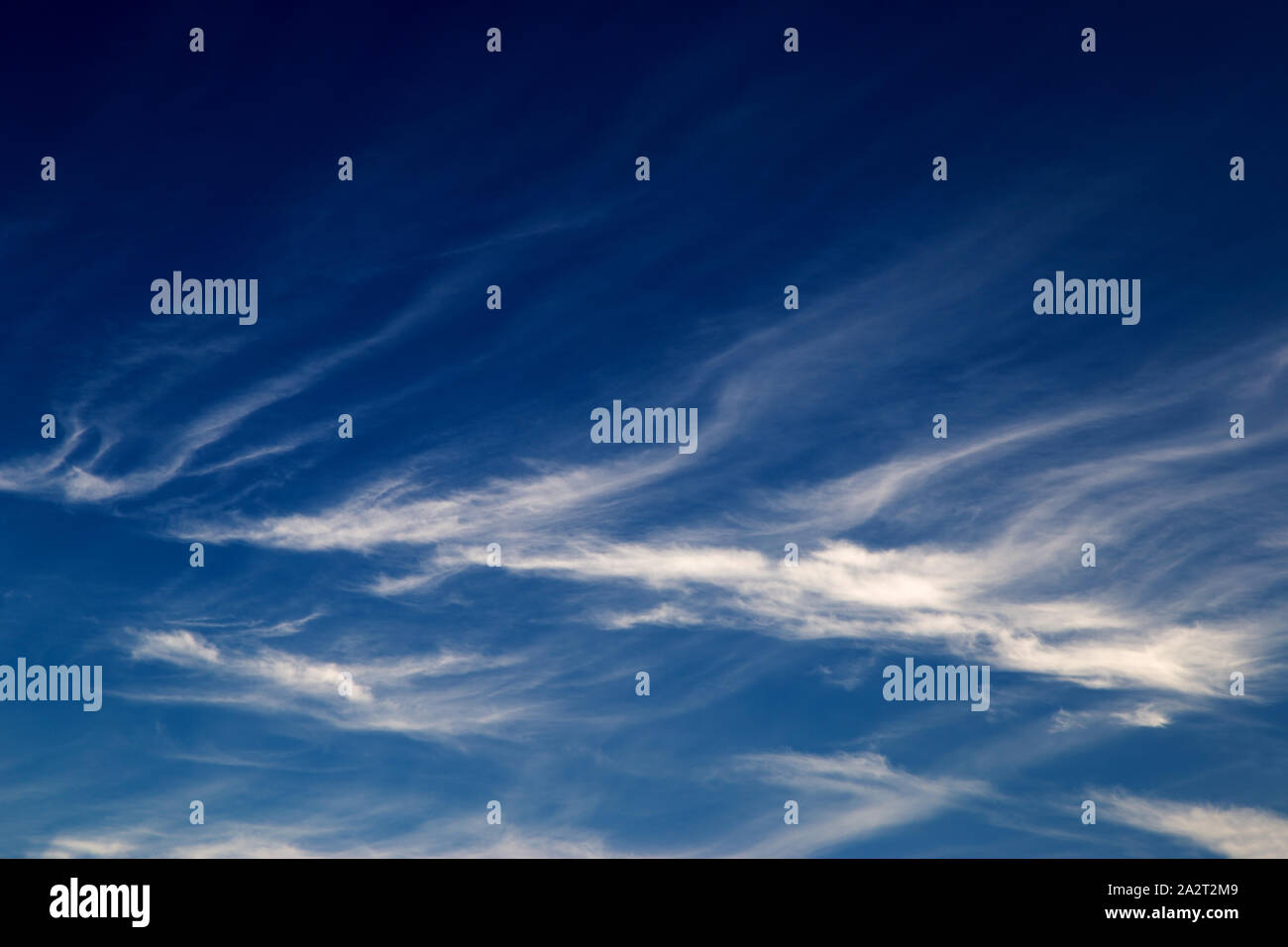 Wispy cirrus clouds against a deep blue sky Stock Photo