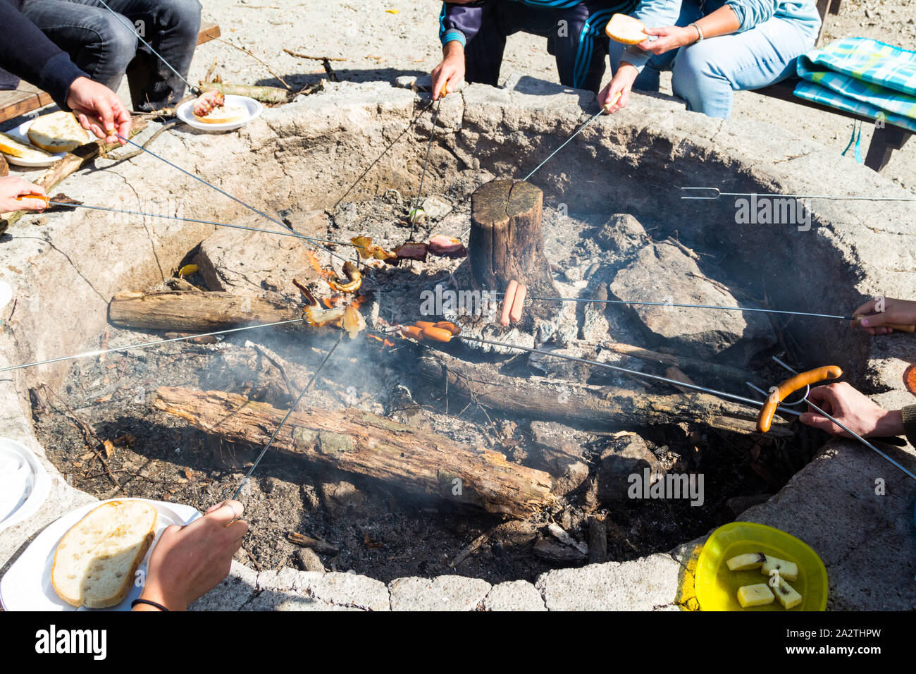 Szalonnasutes (outdoor roasting fatty bacon and frankfurter on skewer) over glowing smoldering smouldering wood logs in Sopron, Hungary Stock Photo