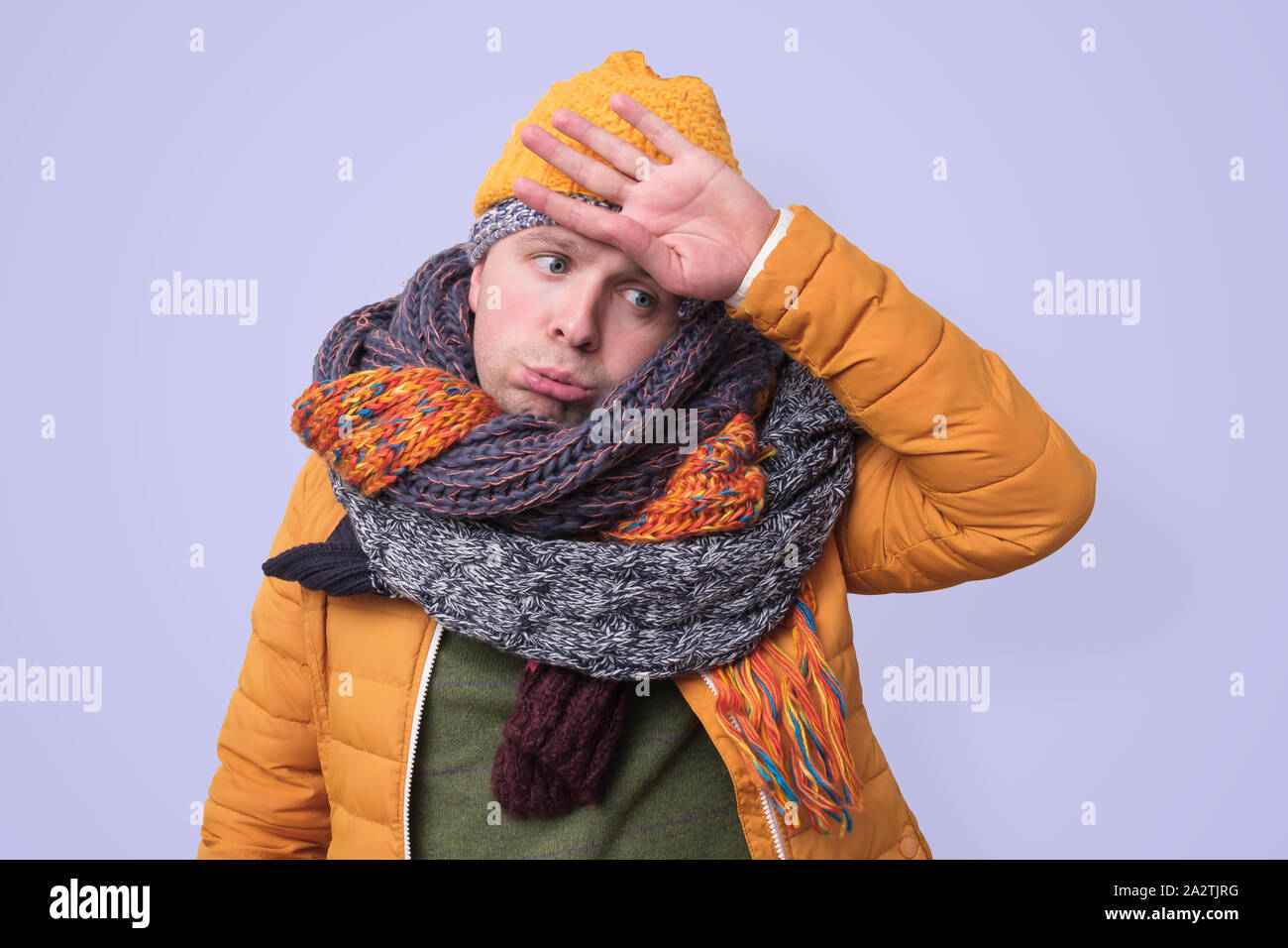Tired caucasian funny man in several hats and scarfs in stressed Stock Photo