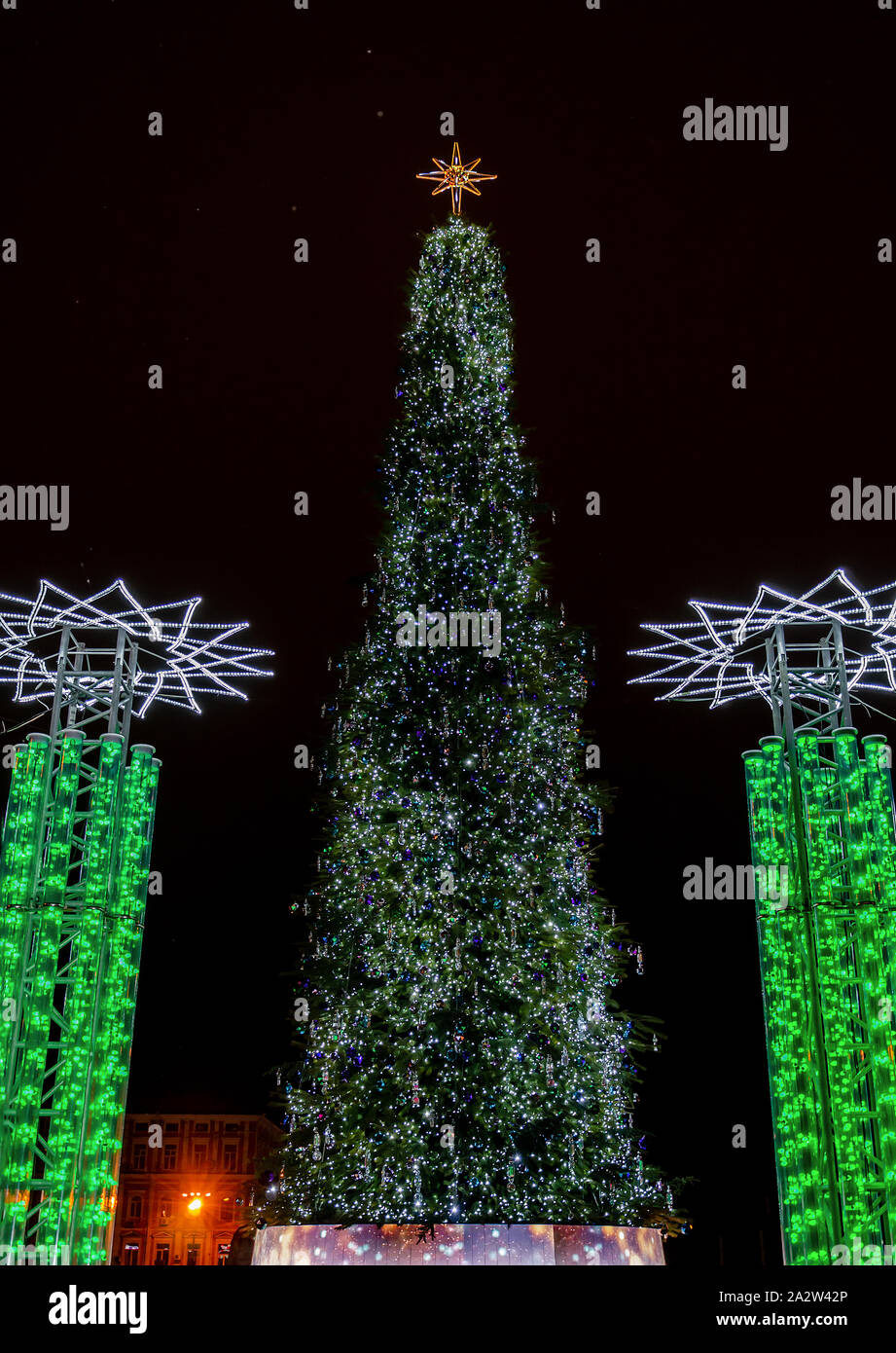 tall christmas tree with garland and decorations, frosty winter evening