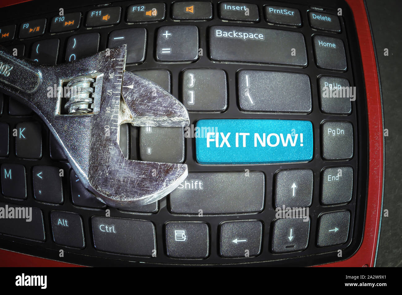 Fix it now blue button on a dirty computer keyboard with wrench tool. Fish eye effect. Stock Photo