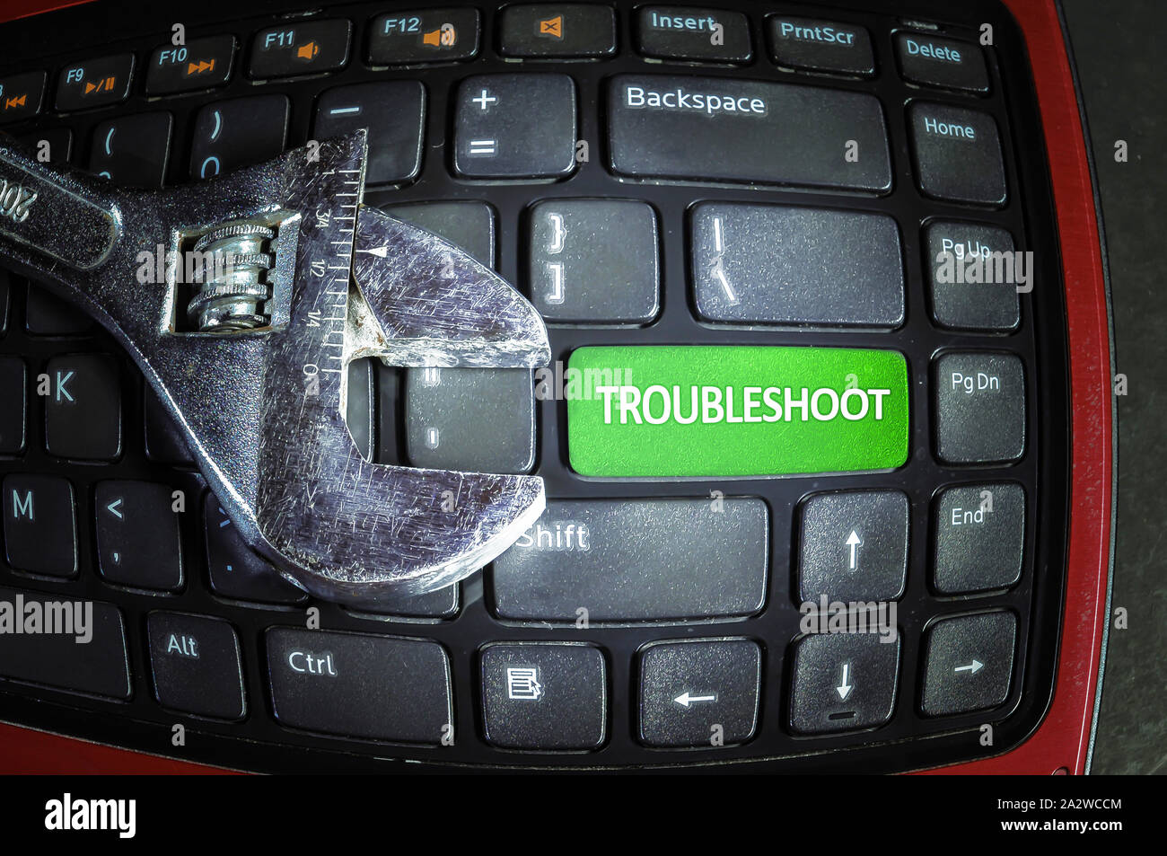 Fish eye effect. Troubleshoot green button on dirty computer keyboard with wrench tool. Stock Photo