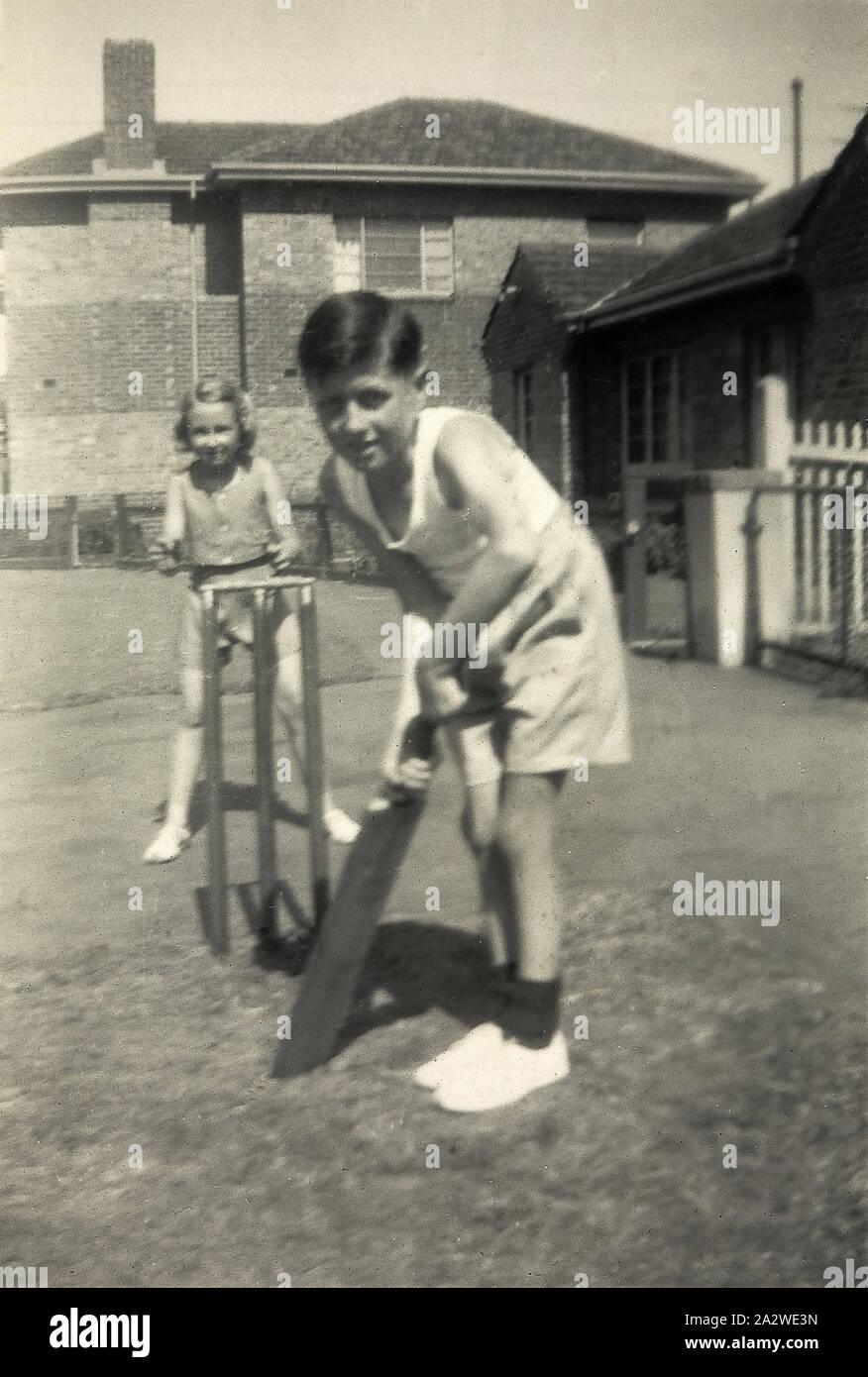 Digital Photograph - Boy & Girl Playing Cricket in Front Yard, Prahran, 1948, Black and white photograph showing Kevin Greenhatch, aged 8, playing cricket with Valerie McKrall in December 1948. Kevin and Valerie are on the footpath outside Kevin's family home in Prahran, an inner eastern suburb of Melbourne Stock Photo