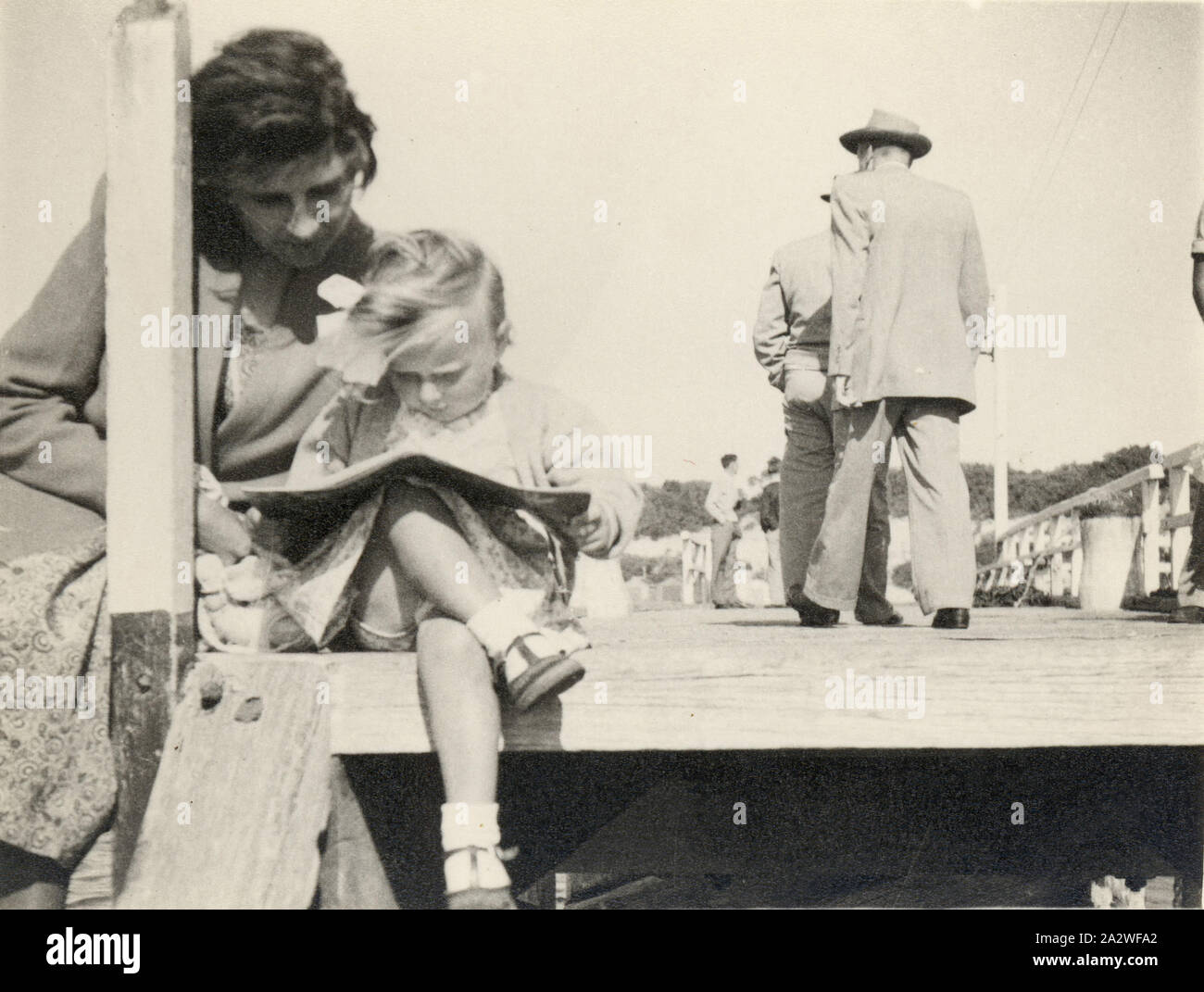 Photograph - Eileen & Susan Leech Sitting Reading on Frankston Pier, Frankston, circa 1954, Photograph of Eileen Leech and her daughter Susan sitting on the end of Frankston Pier, reading a book, Frankston, Melbourne, circa 1954. Susan had migrated with her parents Eileen and James Leech to Melbourne from England in 1953 and they returned to England in 1956. James and Eileen Leech and their two and a half year old daughter Susan migrated from Manchester, England in November 1953 under Stock Photo