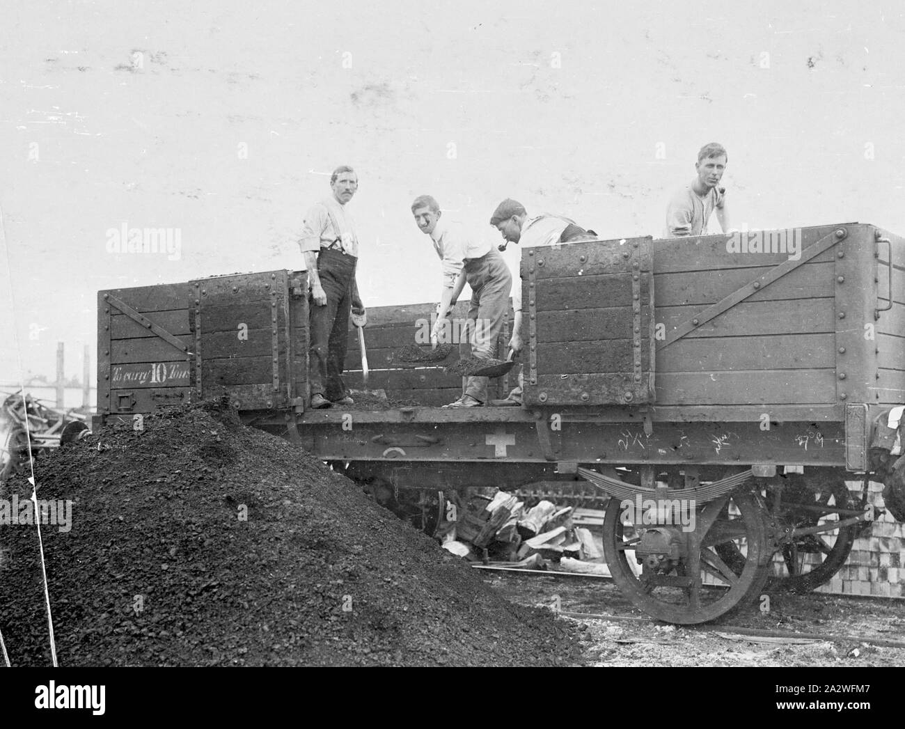 Photograph - Staff Unloading Coal, Sunshine, Victoria, 1911, Black and white photograph of office staff at Sunshine Harvester Works unloading coal from the Railway Trucks at the factory during the 1911 strike. Photograph is located in an album: Volume No.1: 'Views of Factories and Branches', page 10. This is one of 25 albums that provide detailed visual documentation of the activities of the McKay enterprise. a collection of Stock Photo