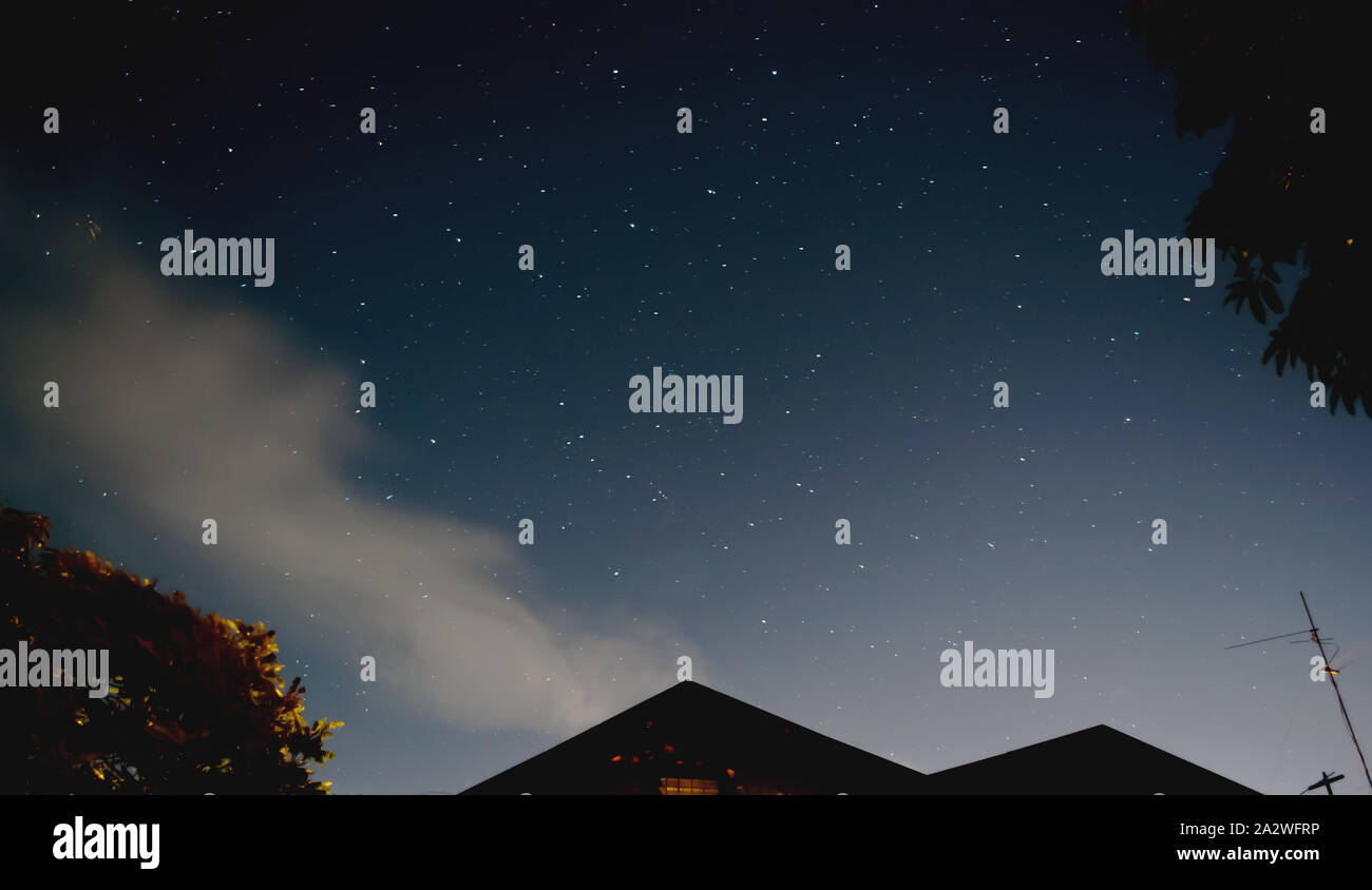 Night Sky View with Stars. Low angle shot. House triangular roof. Stock Photo