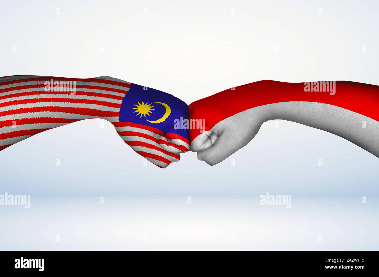 Fist bump of Malaysian and Indonesian flags. Two hands with painted flags of Malaysia and Indonesia Flag fist bumping as a symbol of unity. Stock Photo