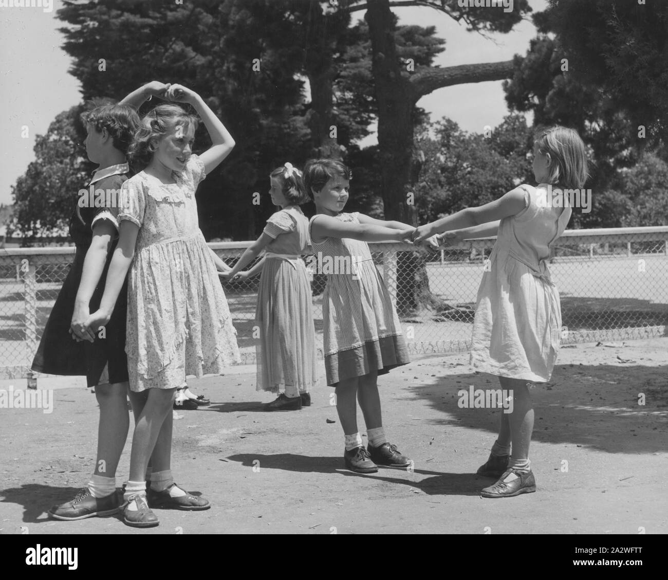 Photograph - Girls Playing 'Wash the Dishes' Game, Dorothy Howard Tour, Melbourne, 1954, Black and white photograph depicting three pairs of girls playing 'Wash the Dishes, Dry the Dishes, Turn the Dishes Over' in a government school playground in Melbourne, Victoria, 1954. It is one of a group of photographs probably taken by American folklorist Dr Dorothy Howard while she was studying children's games and playlore in Australia under a Fulbright research grant,1954-1955. Her Stock Photo