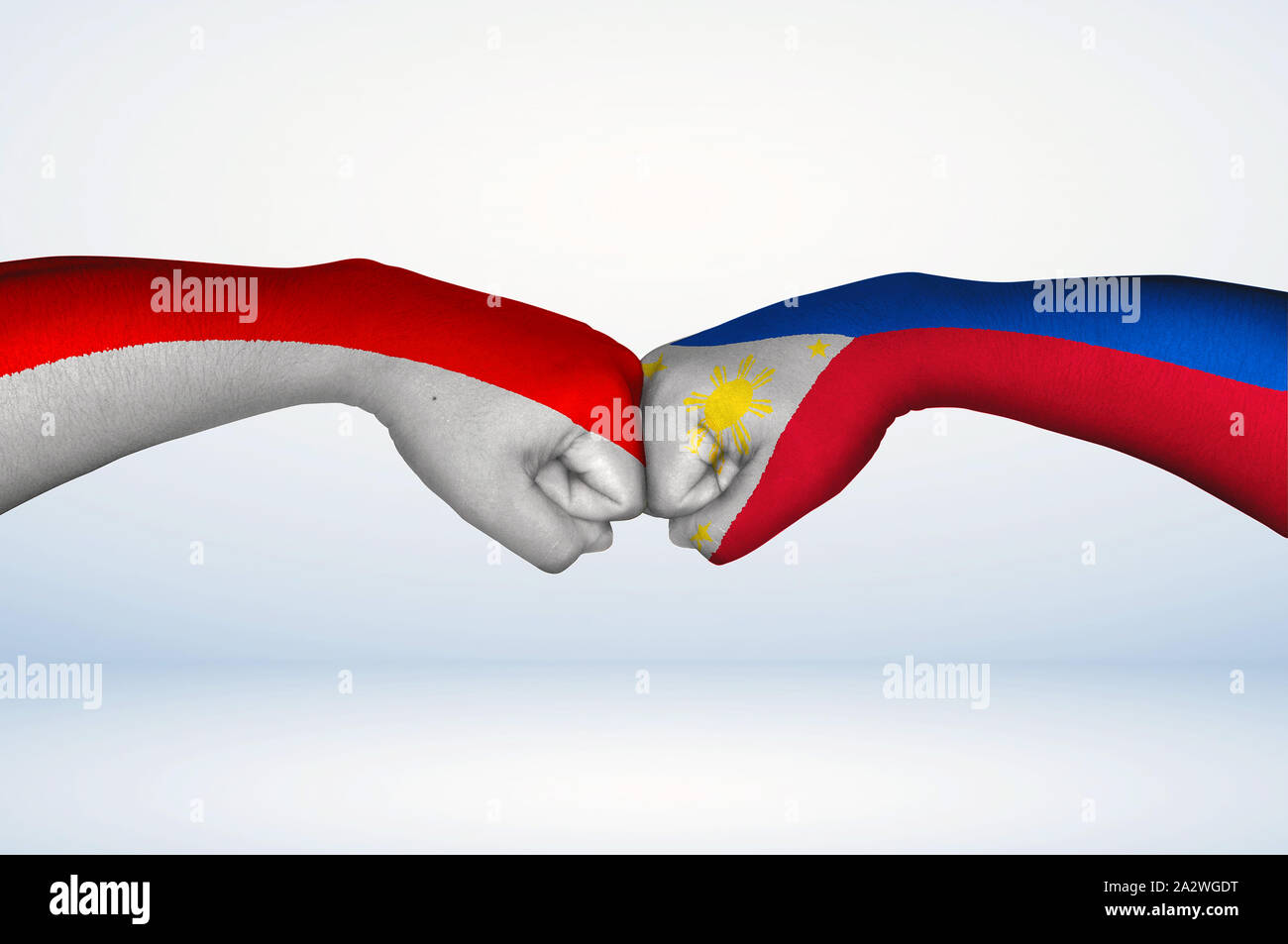 Fist bump of Filipino and Indonesian flags. Two hands with painted flags of Philippines and Indonesia Flag fist bumping as a symbol of unity. Stock Photo