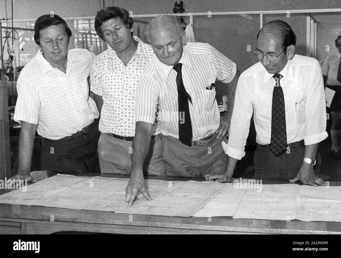 Digital Photograph - Staff Reviewing Engineering Plans, Kodak Australasia Pty Ltd, Coburg, circa 1970s, Black and white digital photograph of four Kodak Australasia Pty Ltd staff reviewing engineering plans circa 1970s. The man second from the right is Norm Ducksbury. This photograph was donated by former Research Laboratory staff member Norm Ducksbury, who was appointed Chief Chemist in the Laboratory at Abbotsford in 1958, and was later Manager of Chemistry Research at Coburg from 1960 Stock Photo