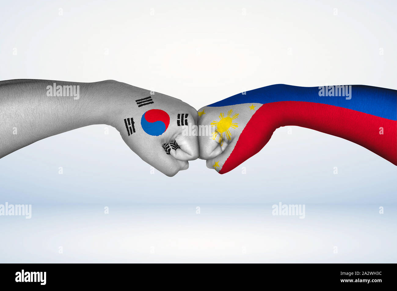 Fist bump of Filipino and South Korean flags. Two hands with painted flags of Philippines and South Korea Flag fist bumping as a symbol of unity. Stock Photo