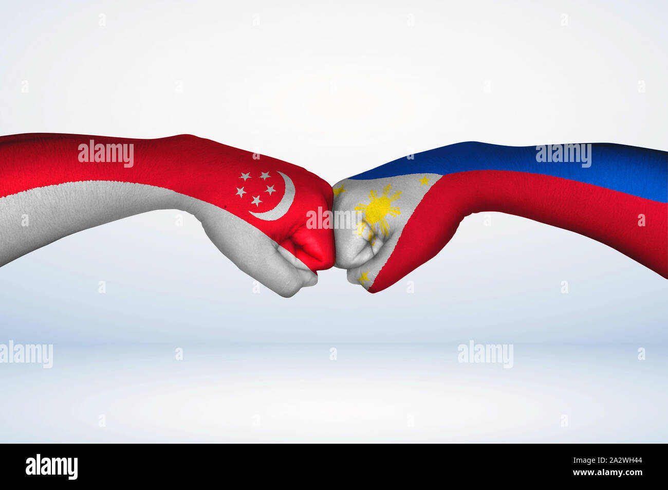 Fist bump of Filipino and Singaporean flags. Two hands with painted flags of Philippines and Singapore Flag fist bumping as a symbol of unity. Stock Photo