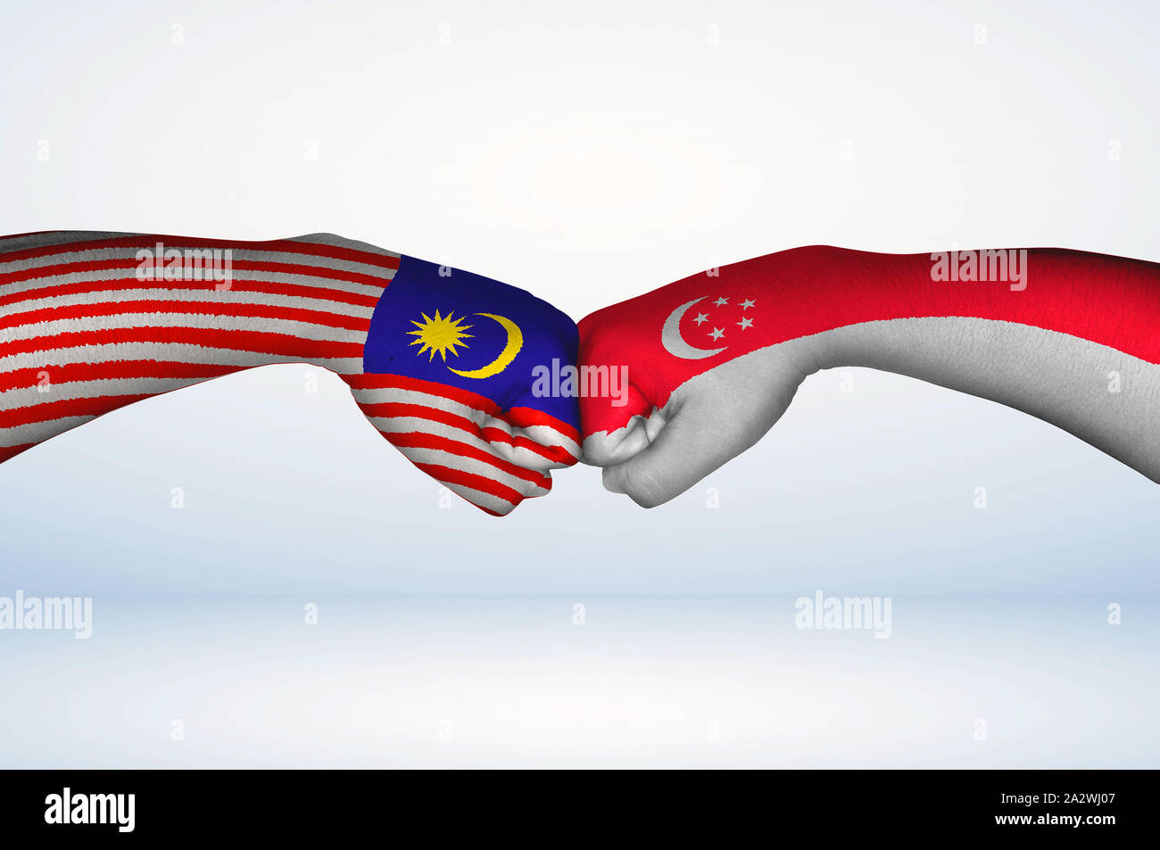 Fist bump of Malaysian and Singaporean flags. Two hands with painted flags of Malaysia and Singapore Flag fist bumping as a symbol of unity. Stock Photo
